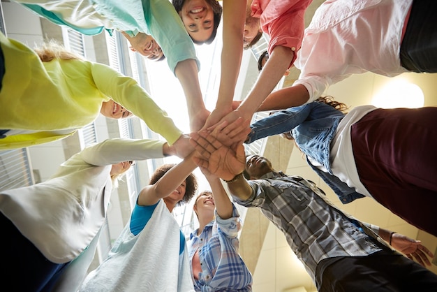 concept d'éducation, d'école, de travail d'équipe et de personnes - groupe d'étudiants internationaux avec les mains les unes sur les autres au-dessus de la table