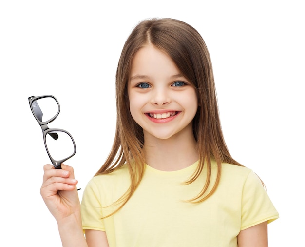 Photo concept d'éducation, d'école et de vision - jolie petite fille souriante tenant des lunettes noires