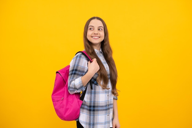 Concept d'éducation. enfant en chemise à carreaux sur fond jaune. 1er septembre. enfance heureuse. enfant avec sac d'école. une adolescente positive porte un sac à dos. retour à l'école. journée du savoir.