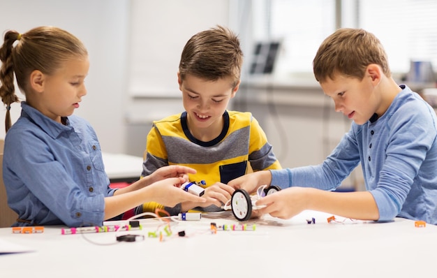 concept d'éducation, d'enfants, de technologie, de science et de personnes - groupe d'enfants heureux construisant des robots à la leçon d'école de robotique