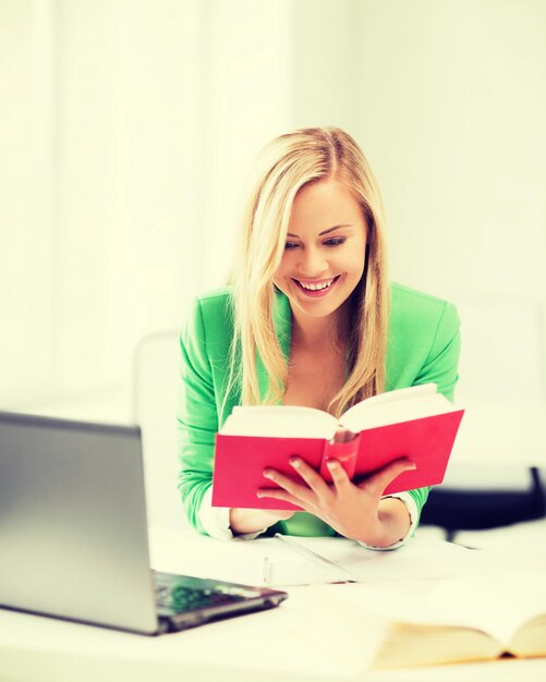 concept d'éducation - fille étudiante souriante lisant un livre au collège