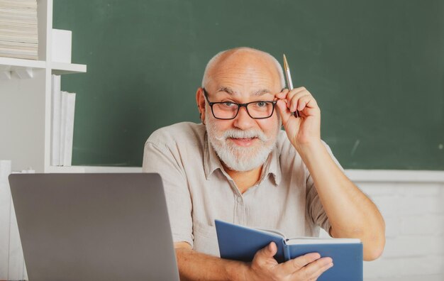 Concept d'éducation grand-père portrait d'un enseignant mature ou d'un professeur tuteur travaillant à table en coll