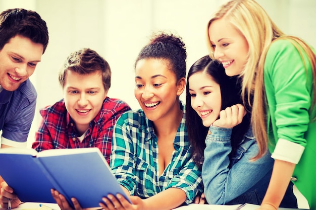 Photo concept d'éducation - groupe d'étudiants lisant un livre à l'école