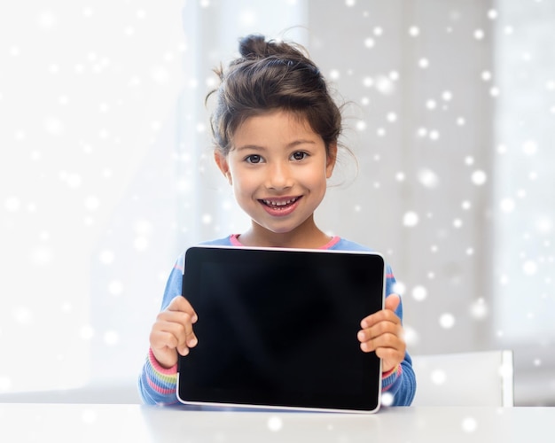 concept d'éducation, d'hiver, de technologie et de personnes - petite fille souriante avec tablette pc à la maison