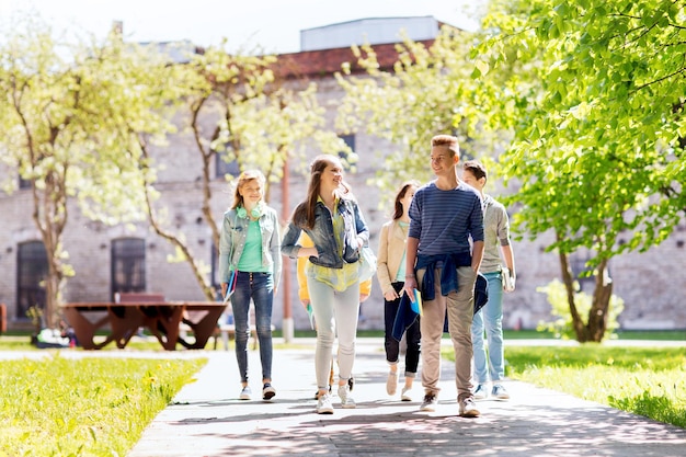 concept d'éducation, de lycée, de communication et de personnes - groupe d'étudiants adolescents heureux marchant à l'extérieur