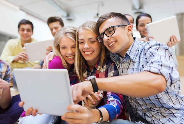 concept d'éducation, de lycée, de technologie et de personnes - groupe d'étudiants souriants avec des ordinateurs tablettes prenant des photos ou des vidéos à l'intérieur