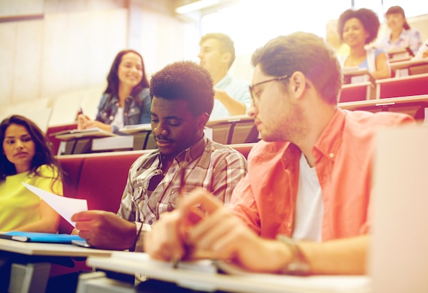 Photo concept d'éducation, de lycée, d'université, d'apprentissage et de personnes - groupe d'étudiants internationaux avec un test dans une salle de conférence