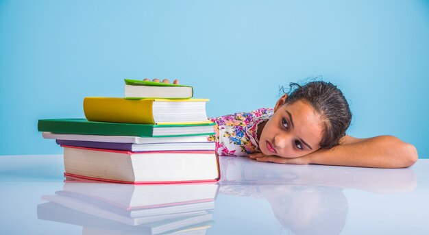 Concept d'éducation à la maison - Jolie petite fille indienne ou asiatique qui étudie à la maison avec une pile de livres, un globe éducatif, etc. Mise au point sélective