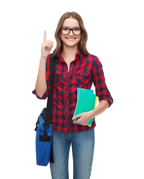 concept d'éducation et de personnes - étudiante souriante à lunettes avec sac et cahiers montrant la direction