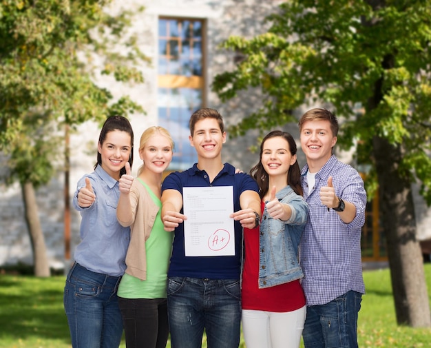 concept d'éducation et de personnes - groupe d'étudiants souriants debout et montrant des tests et des pouces vers le haut