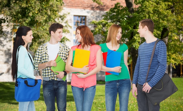 concept d'éducation et de personnes - groupe d'étudiants souriants avec des sacs et des dossiers en discussion