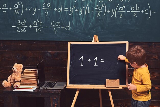Photo concept d'éducation petit garçon résolvant l'équation sur le tableau formation préscolaire pour enfant intelligent