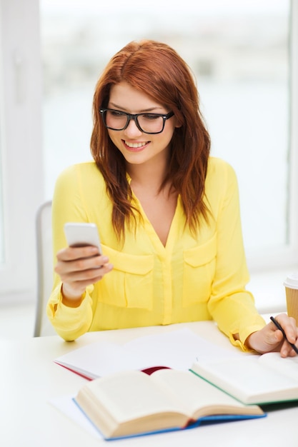 concept d'éducation et de technologie - étudiante souriante à lunettes avec smartphone, livres et café à emporter à l'école