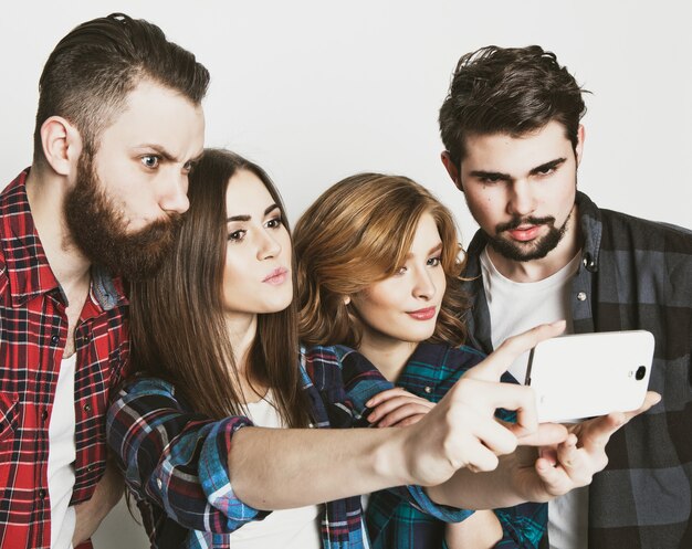Concept d'éducation, de technologie et de personnes: groupe d'étudiants prenant selfie avec smartphone sur un espace blanc Tonification à la mode spéciale.