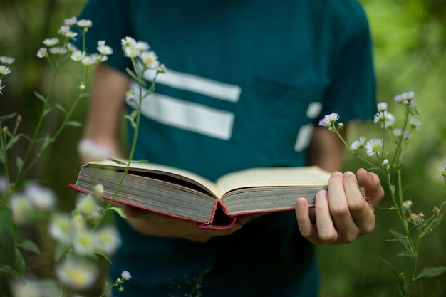 Concept d'éducation et de vacances adolescent tient un livre dans ses mains dans la nature