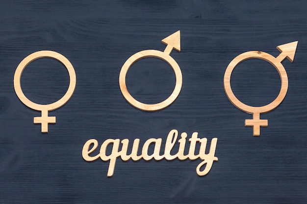 Le concept d'égalité des sexes. symboles de genre d'un homme et d'une femme sur un fond en bois noir, vue de dessus