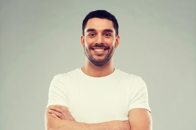 concept d'émotion et de personnes - jeune homme souriant heureux avec les bras croisés sur fond gris