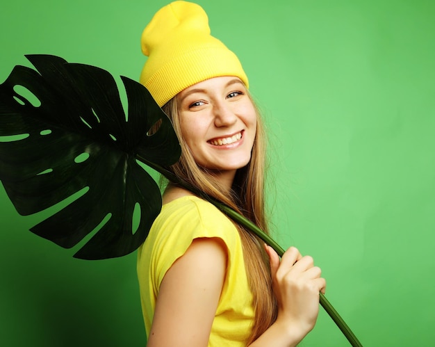 Concept d'émotion et de personnes de style de vie Jeune belle femme portant des vêtements décontractés jaunes tenant des feuilles de monstera