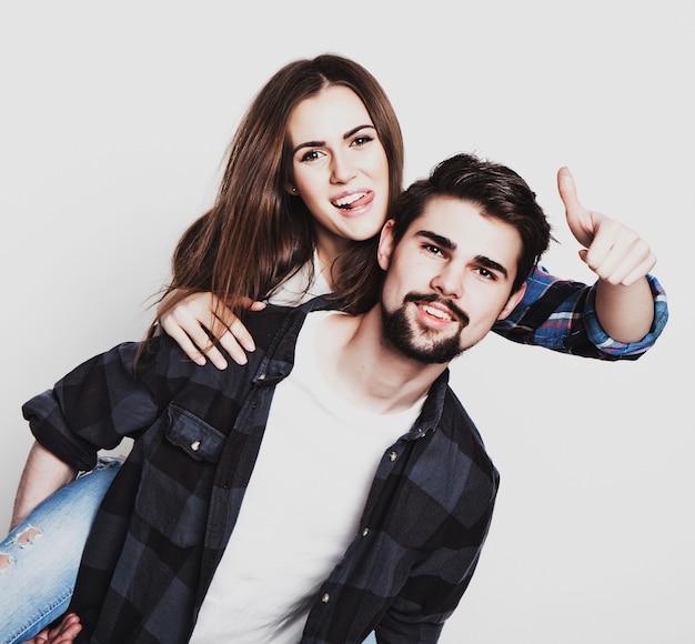 Concept émotionnel, style de vie, bonheur et personnes : couple d'amoureux heureux. Jeune homme ferrouillant sa petite amie. Prise de vue en studio sur fond blanc. Photos spéciales de tonification à la mode.