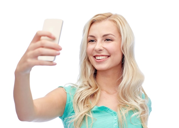 concept d'émotions, d'expressions et de personnes - heureuse jeune femme souriante ou adolescente prenant un selfie avec un smartphone