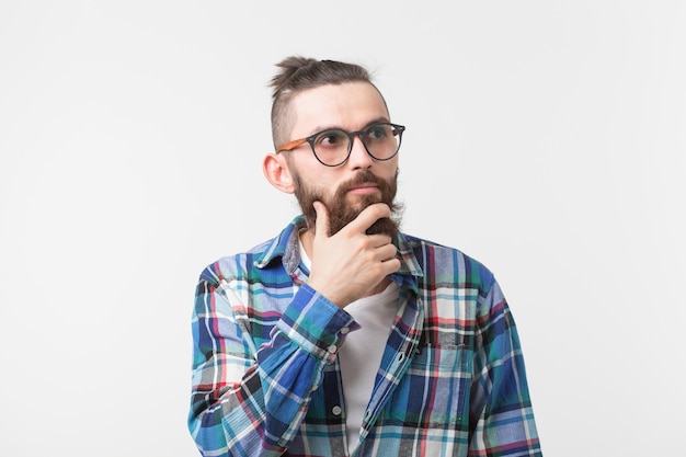 Concept d'émotions et de personnes - Homme hipster barbu pensant à quelque chose sur fond blanc.