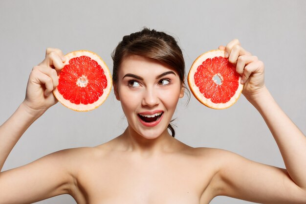 Concept d'émotions, de santé, de personnes, de nourriture et de beauté - Portrait de beauté d'une femme heureuse tenant un pamplemousse, portrait émotionnel. la fille est surprise