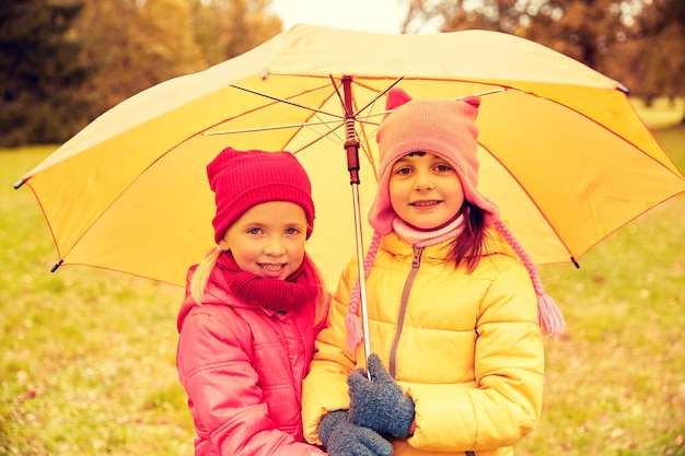 concept d'enfance, d'amitié, de saison, de météo et de personnes - petites filles heureuses avec parapluie dans le parc d'automne