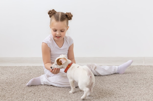 Concept d'enfance, d'animaux de compagnie et de chiens - Petite fille de chiot et d'enfant en chemise blanche s'amusant.