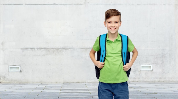 concept d'enfance, d'école, d'éducation et de personnes - heureux garçon étudiant souriant avec sac d'école sur fond de rue urbaine