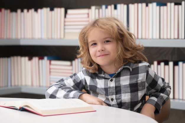 Concept d'enfance et d'éducation Enfant lisant un livre rouge dans la bibliothèque Petit étudiant à la bibliothèque de l'école