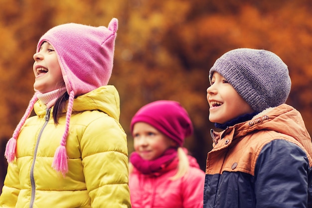 concept d'enfance, de loisirs, d'amitié et de personnes - groupe d'enfants heureux dans le parc d'automne