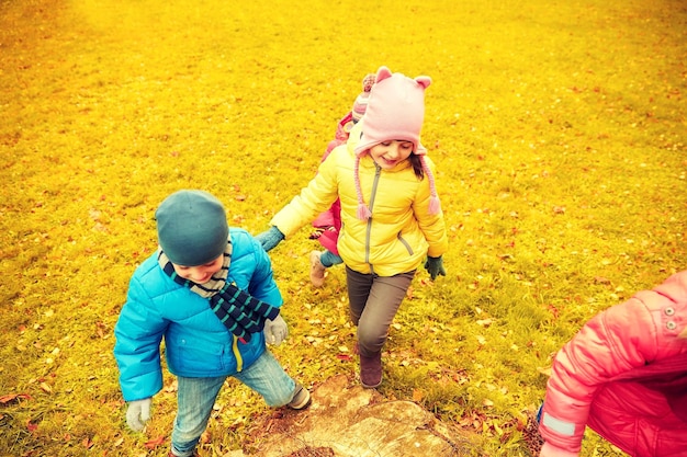 concept d'enfance, de loisirs, d'amitié et de personnes - groupe d'enfants heureux jouant au jeu et s'amusant dans le parc d'automne