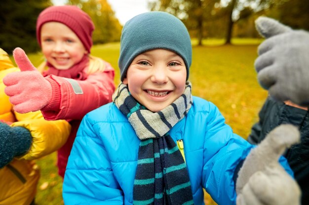 concept d'enfance, de loisirs, d'amitié et de personnes - groupe d'enfants heureux montrant les pouces vers le haut dans le parc d'automne