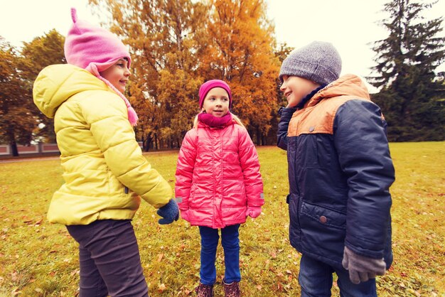 concept d'enfance, de loisirs, d'amitié et de personnes - groupe d'enfants heureux parlant dans le parc d'automne