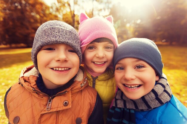 concept d'enfance, de loisirs, d'amitié et de personnes - groupe d'enfants heureux s'embrassant dans le parc d'automne