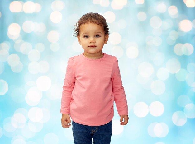 concept d'enfance, de mode, de vêtements et de personnes - beau petit portrait de bébé afro-américain sur fond de lumières de vacances bleues