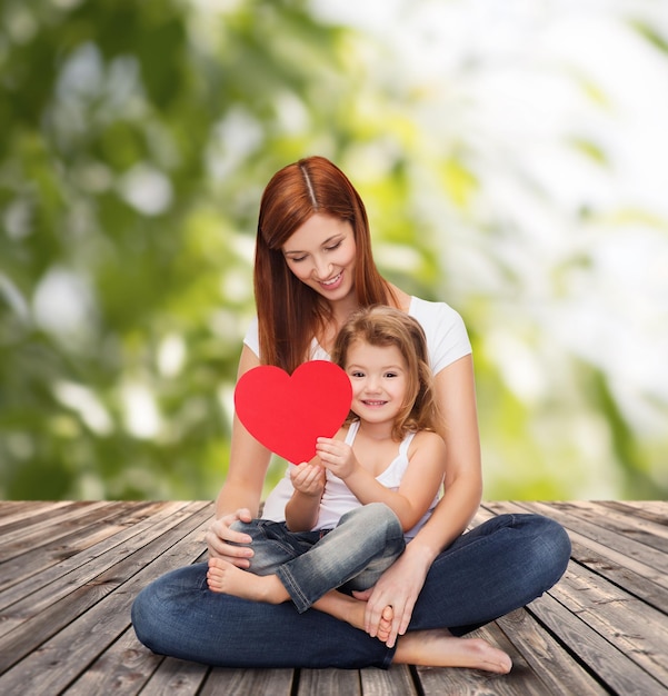 concept d'enfance, de parentalité et de relation - mère heureuse avec une adorable petite fille et un coeur rouge