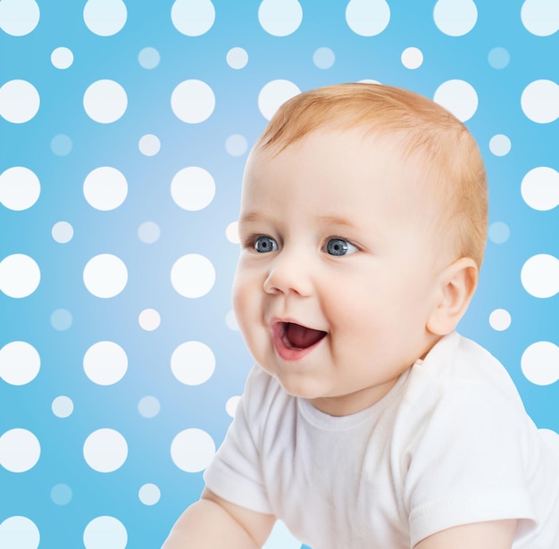 concept d'enfance, de personnes et de bonheur - visage souriant de bébé garçon sur fond de motif à pois bleus et blancs