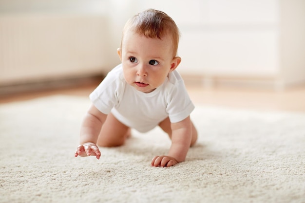 concept d'enfance, de petite enfance et de personnes - petit bébé garçon ou fille rampant sur le sol à la maison