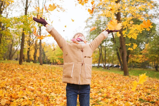 concept d'enfance, de saison et de personnes - petite fille souriante s'amusant dans le parc d'automne