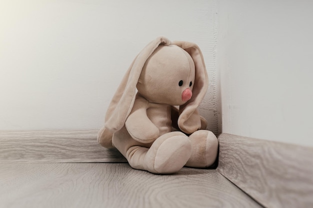 Concept d'enfant de chagrin Lapin jouet assis dans le coin de la maison seul a l'air triste et déçu