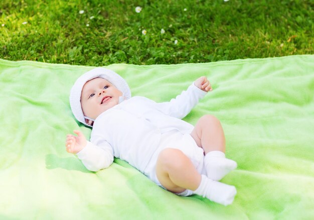 concept d'enfant, d'enfance et de tout-petit - bébé souriant allongé sur une couverture et levant les yeux