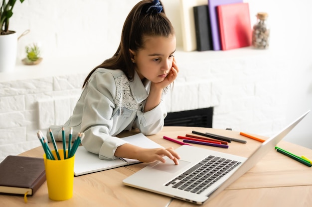 concept d'enfants, d'éducation et d'apprentissage à distance - petite étudiante avec un ordinateur portable à la maison