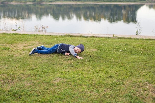 Concept d'enfants et de l'enfance - souriant petit garçon allongé sur l'herbe
