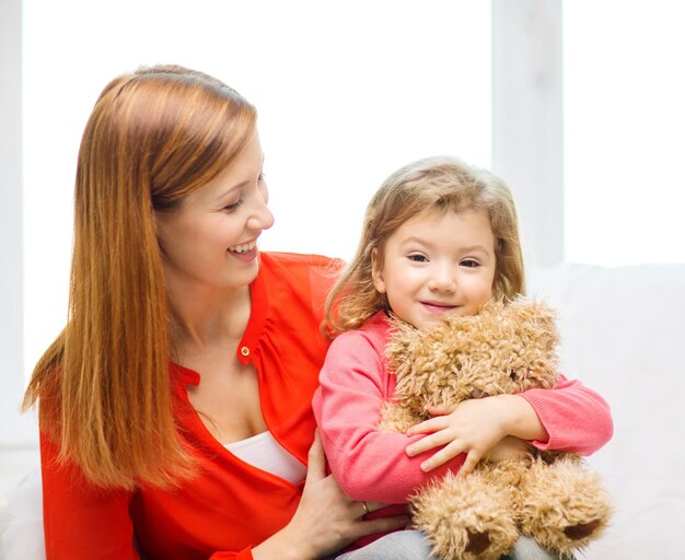 concept d'enfants, de parentalité et de bonheur - heureuse mère et enfant avec ours en peluche à la maison