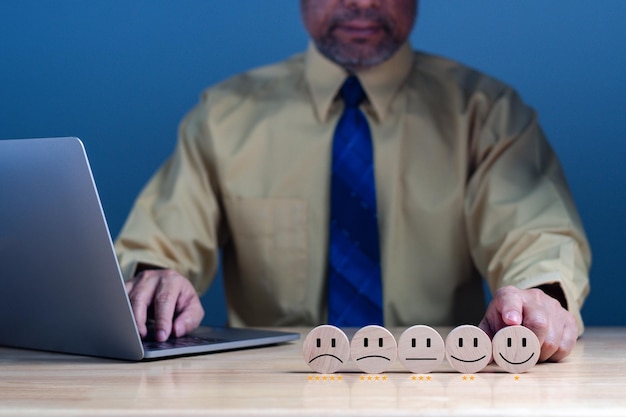 Concept d'enquête de satisfaction Main d'un homme d'affaires pointant et choisit un visage souriant sur un cube de bloc de bois Satisfaction 5 étoiles Meilleurs excellents services aux entreprises notant l'expérience client Espace de copie