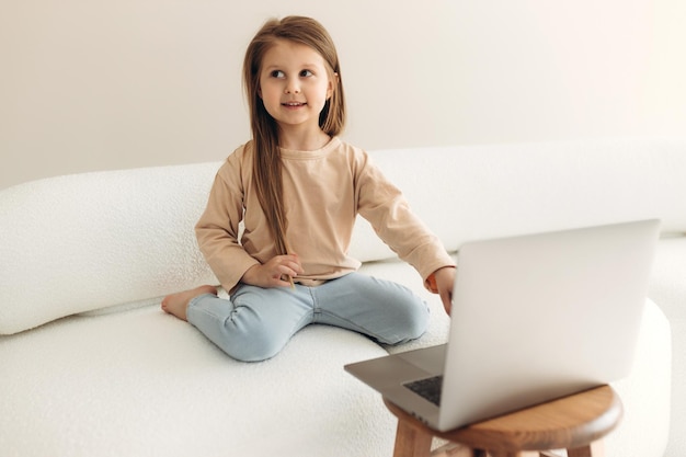 Concept d'enseignement à domicile Mignonne petite fille préadolescente à l'aide d'un ordinateur portable pour étudier en ligne à la maison