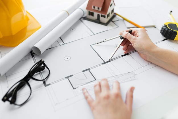 concept d'entreprise, d'architecture, de bâtiment, de construction et de personnes - gros plan des mains d'architecte avec boussole mesurant le plan de la maison d'habitation