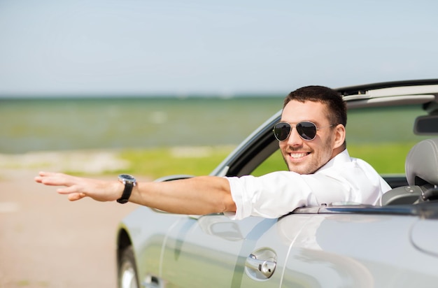 concept d'entreprise automobile, de transport, de loisirs et de personnes - homme heureux conduisant une voiture cabriolet et agitant la main à l'extérieur