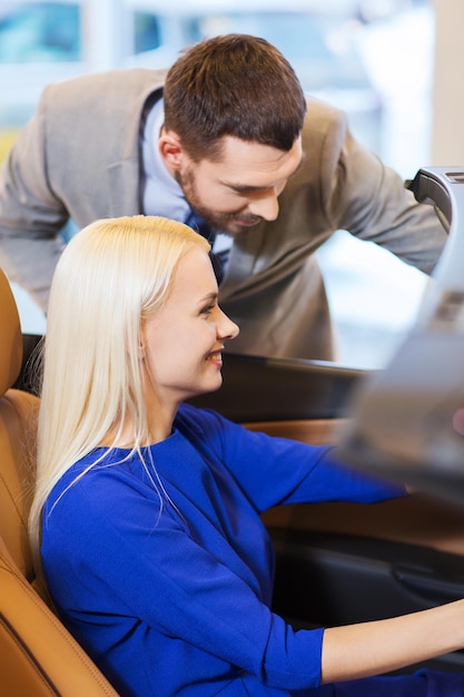 Photo concept d'entreprise automobile, de vente de voitures, de consommation et de personnes - couple heureux achetant une voiture dans un salon de l'auto ou un salon